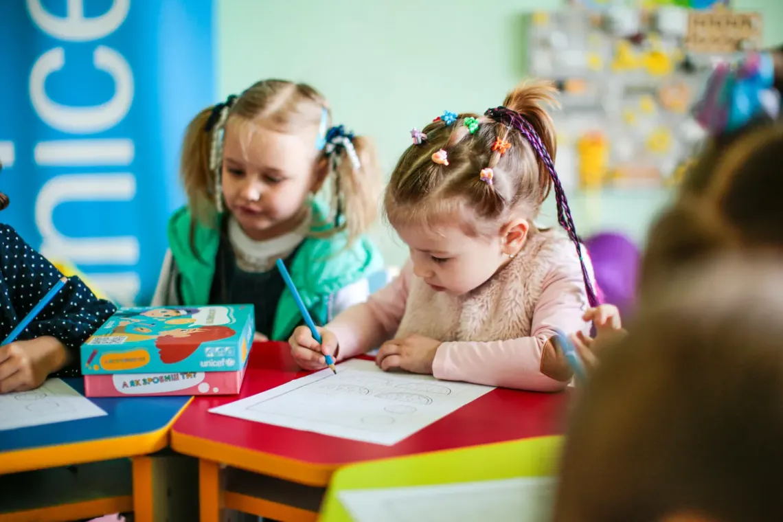 Ukraine. Girls write at their desks during a pre-school development class organized by UNICEF at a local library.