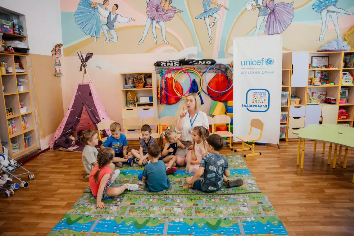 Preschoolers sit on the floor around their teacher during class at early childhood education support centre in Ukraine.