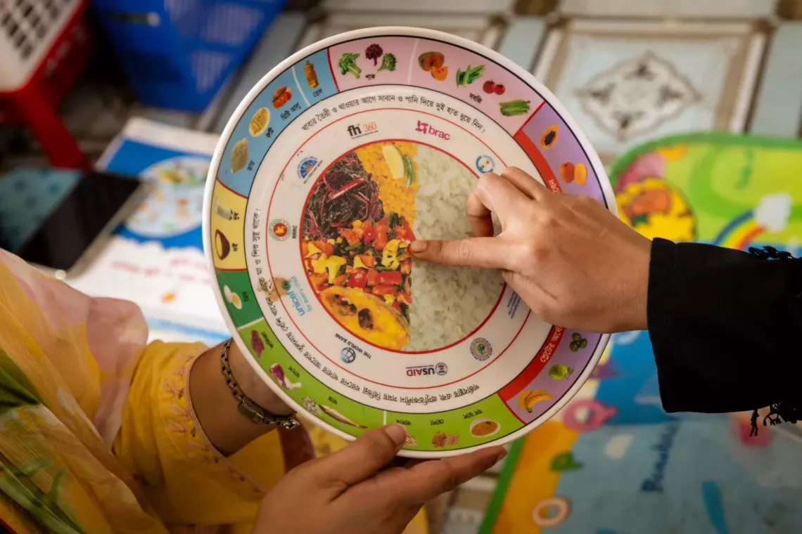 Bangladesh. A nutrition counsellor uses a plate to teach caregivers how to prepare healthy meals for their children.