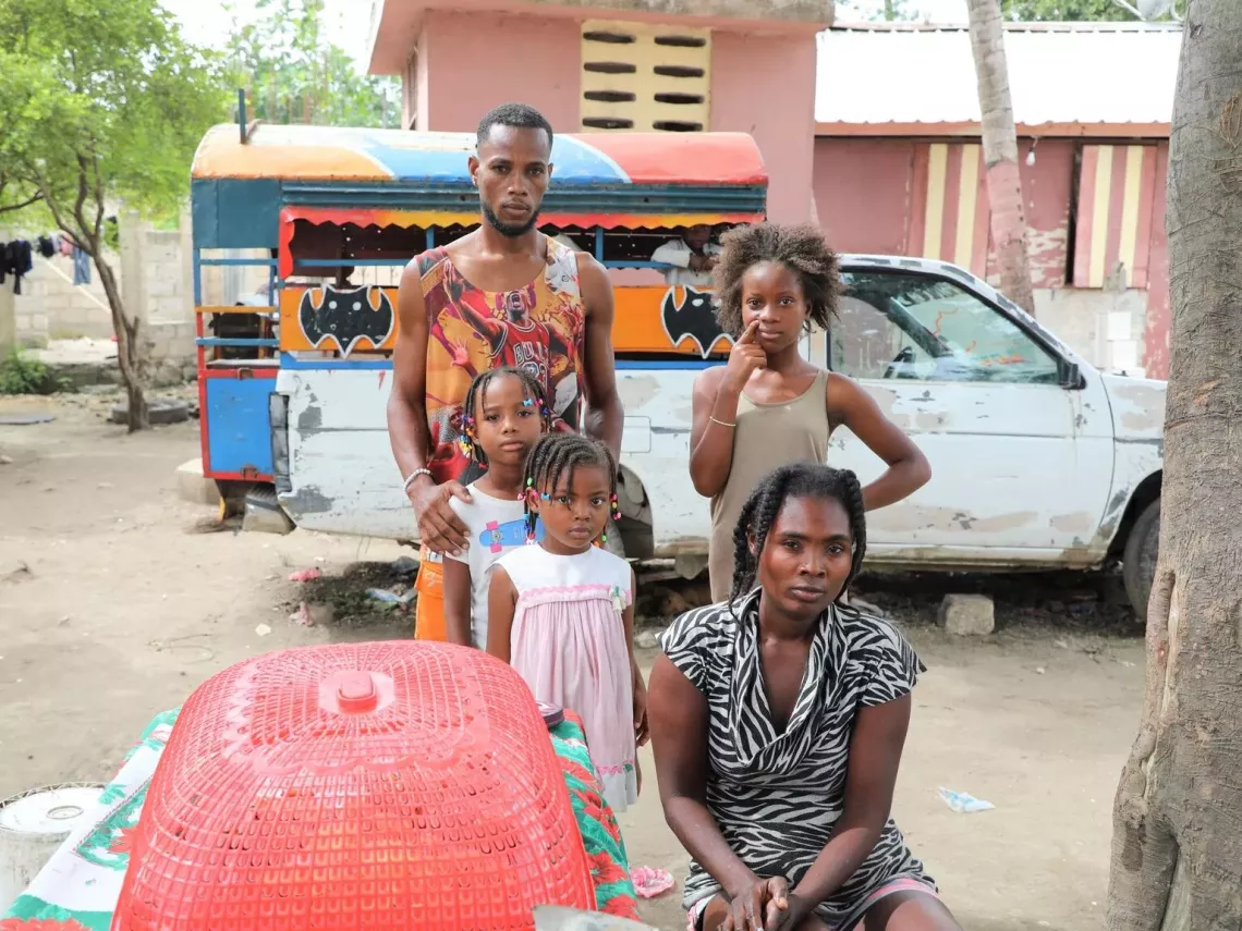 Haiti. A man stands with his three children as their mother sits outside in L&eacute;og&acirc;ne.
