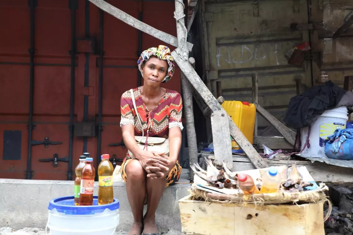 Haiti. A woman sits on a step surrounded by some of the items, such as drinks, that she plans to sell.