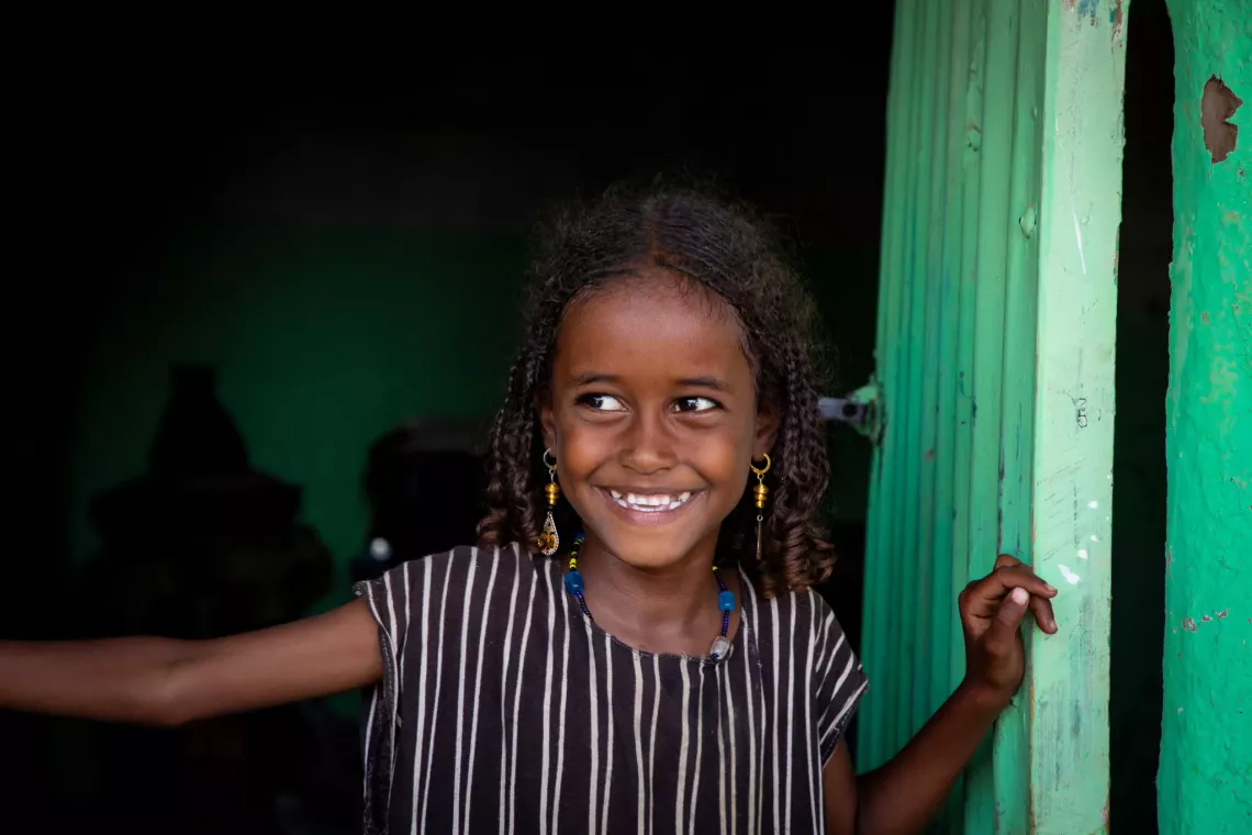 A seven-year-old Kedo smiles while looking out a doorway. Her dream is to become a doctor.