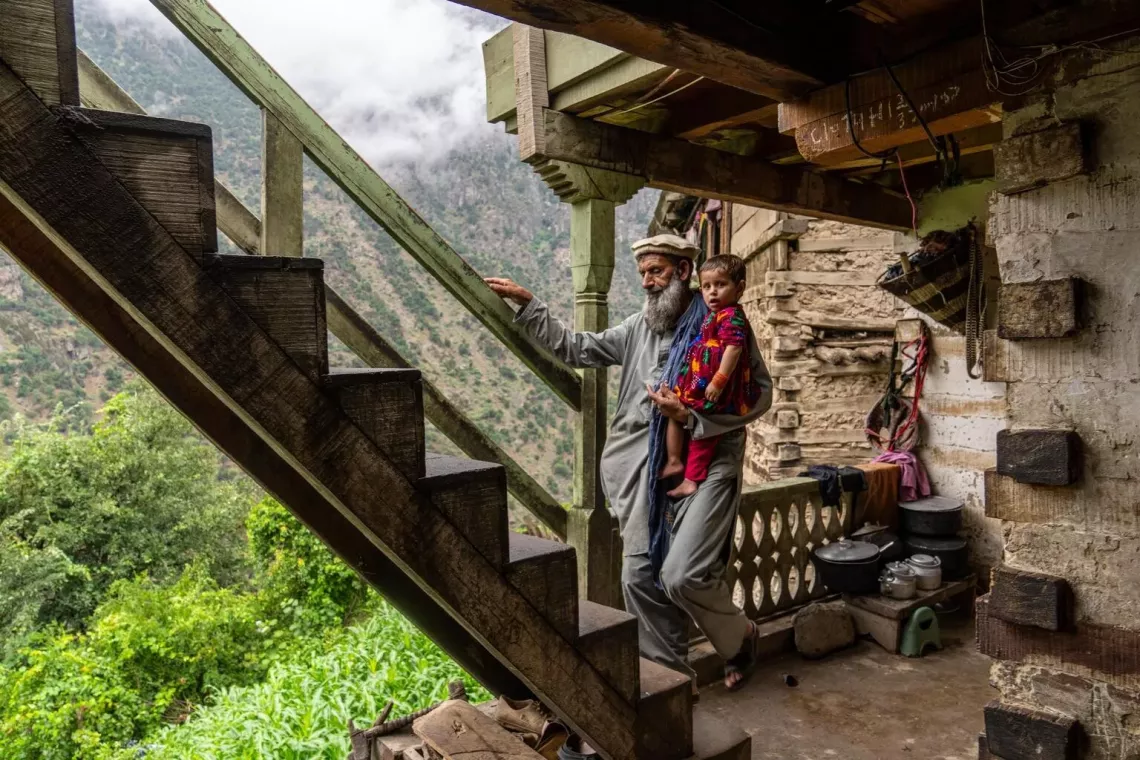 Afghanistan. Roqia&rsquo;s grandfather carries her up a wooden staircase connecting different levels of their mountainside village in Nuristan Province.