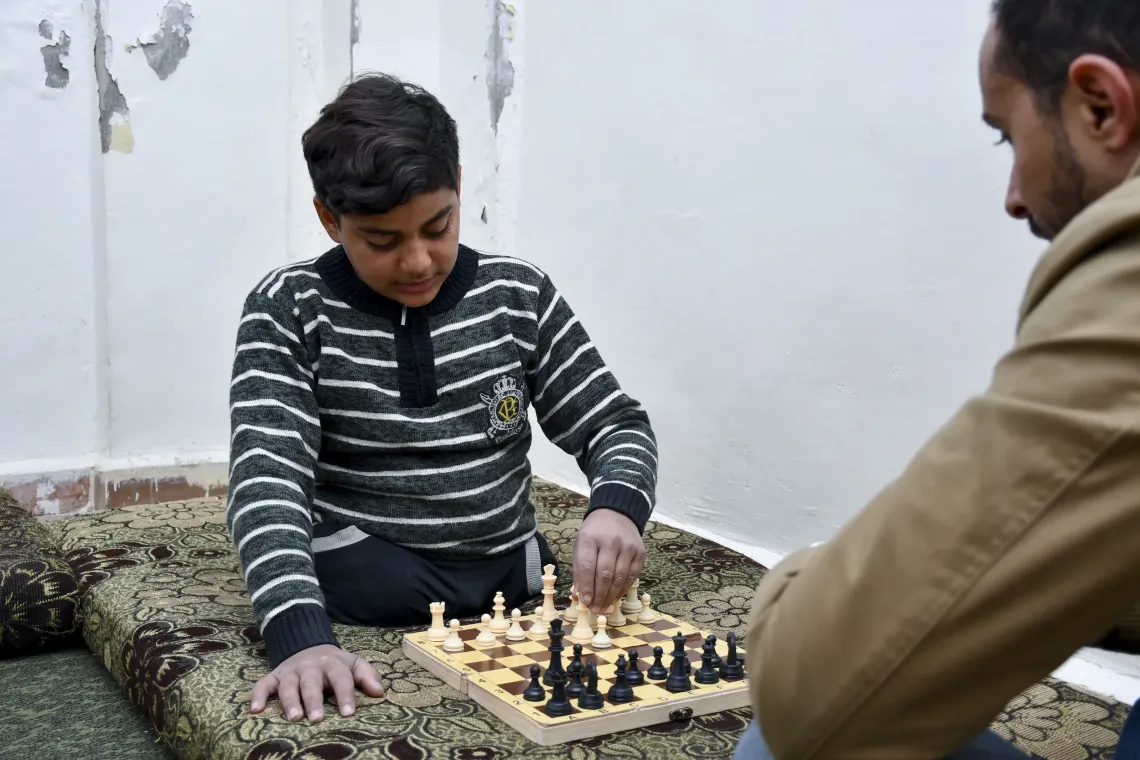 Yahia, 13, plays chess with a member of a UNICEF-supported team at his home in Zabadin village, Rural Damascus, Syria,
