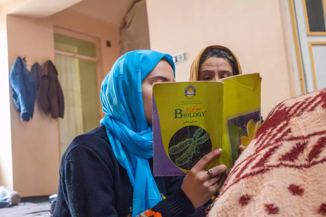 A girl holds up a book in front of her and her mother.