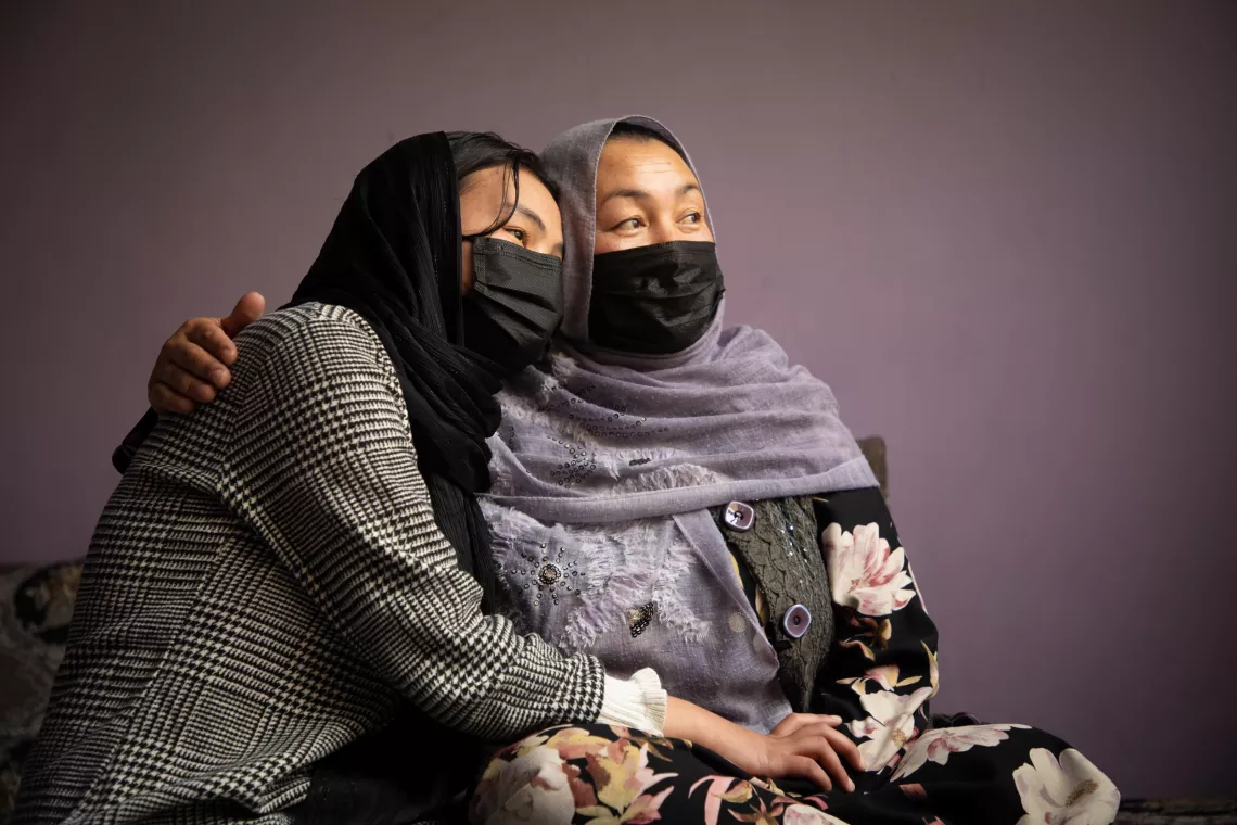 A mother hugs her 15-year-old daughter, who is sitting next to her.
