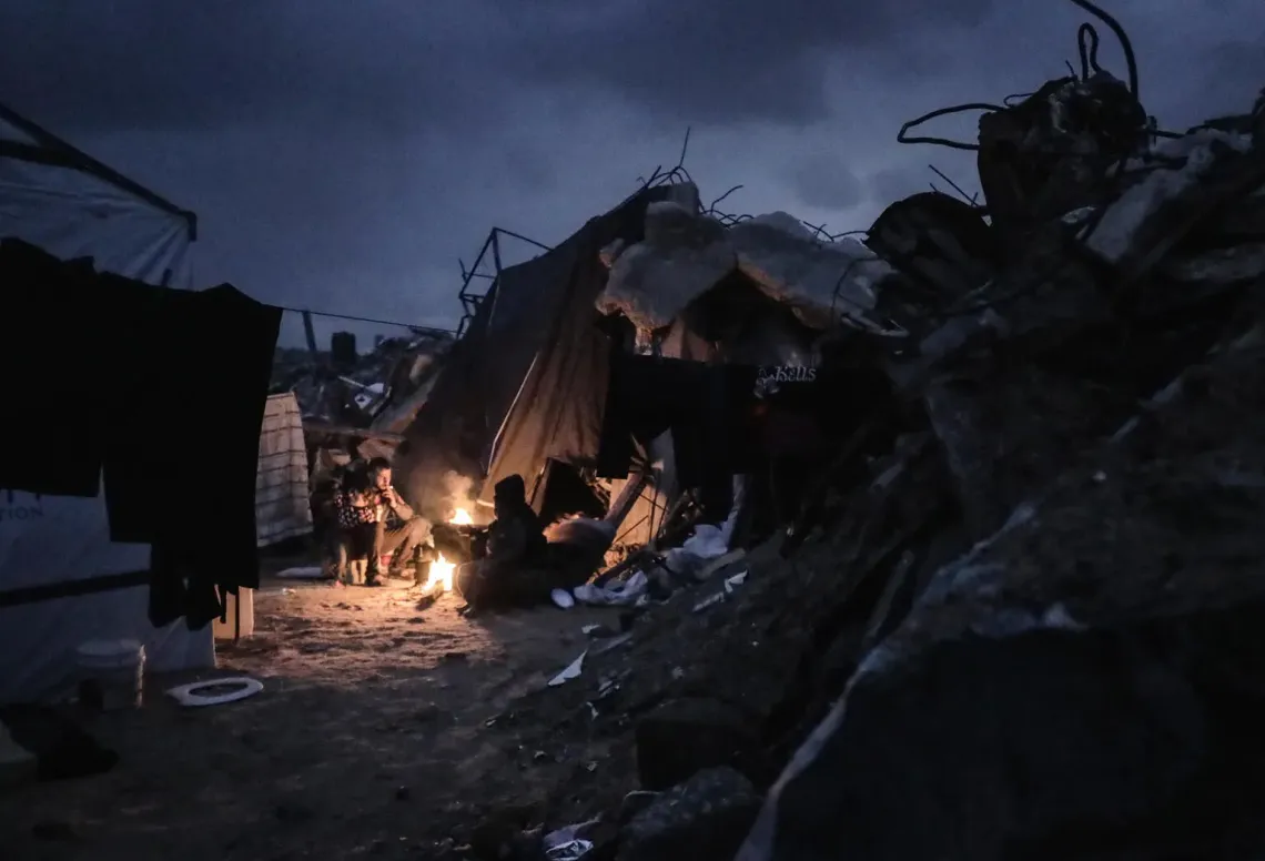 Gaza Strip. A family gathers around a fire outside a tent in Jabalia Camp.