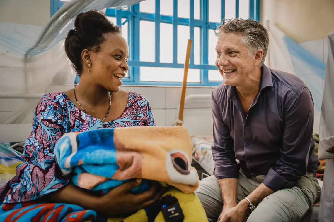 Marthe Nzigire gently holds her two-week-old baby girl, Charmante, as she chats with UNICEF Spokesperson James Elder