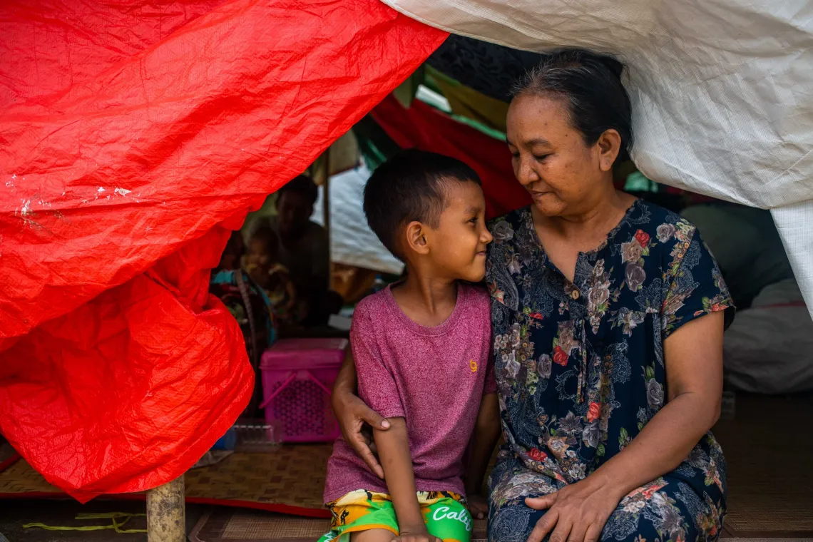 Myanmar. A boy and his mother sit together inside a temporary shelter. 