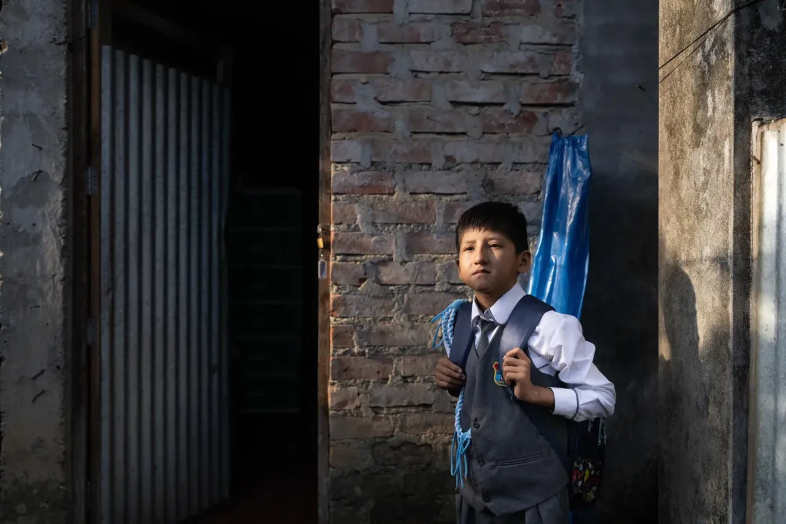 Peru. Hansel, wearing his school uniform, stands outside his home in Ayacucho.