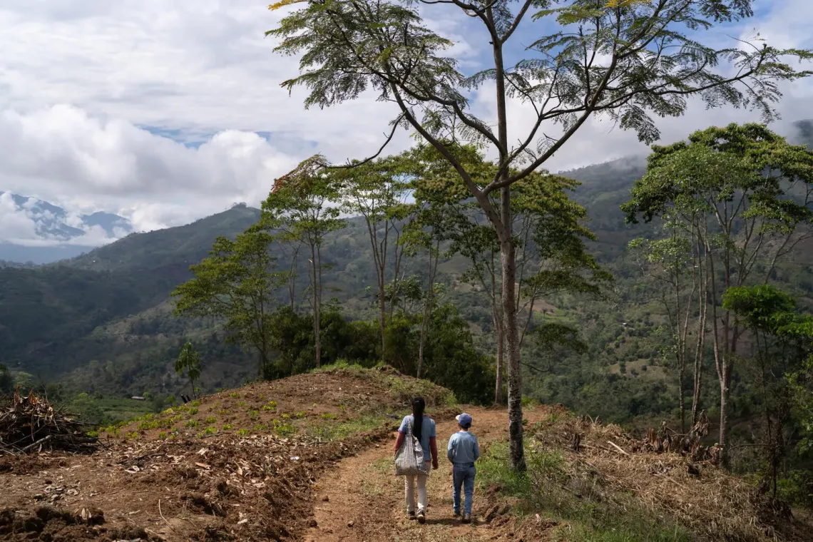 Peru. A boy walks alongside his mother in their crop field on a hill in Ayacucho.