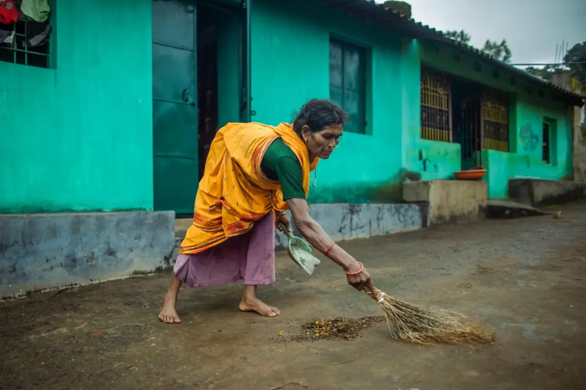 A woman in the village cleans the front of her house. 