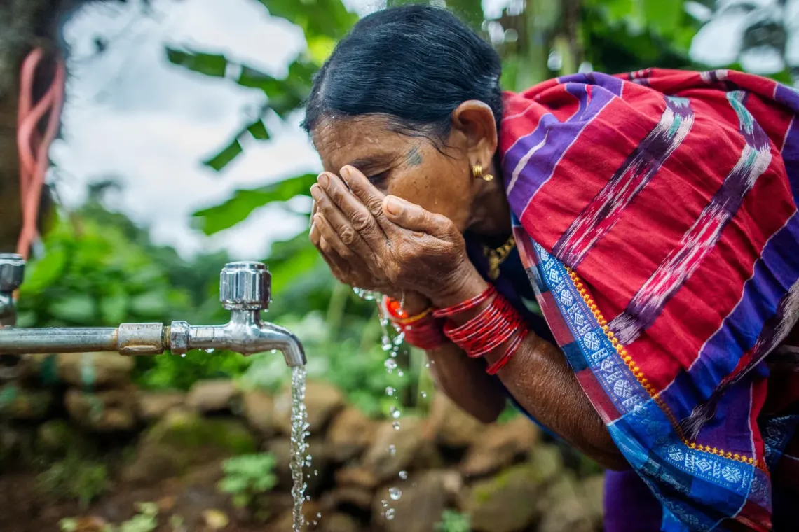 Jhuding drinks water from the solar powered community tap in Bandaguda village. 