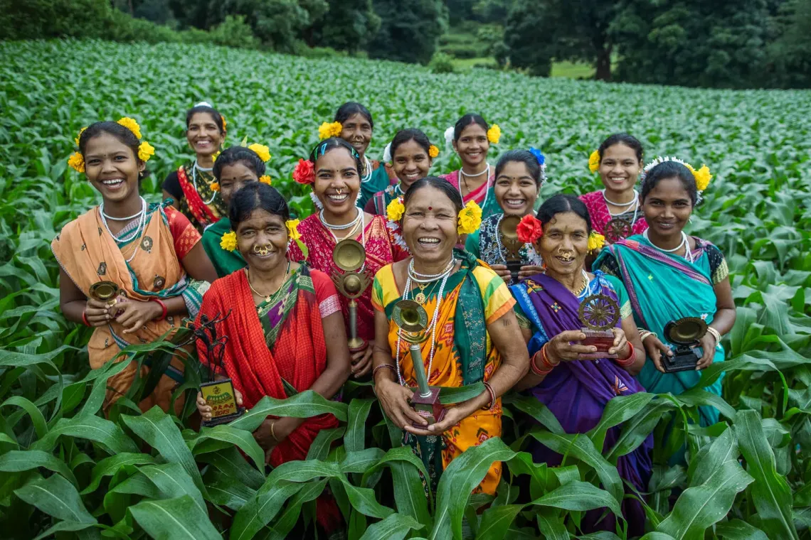 Group portrait of Naranga, Jhuding and Kalpana, along with other SHG members holding awards they have received.