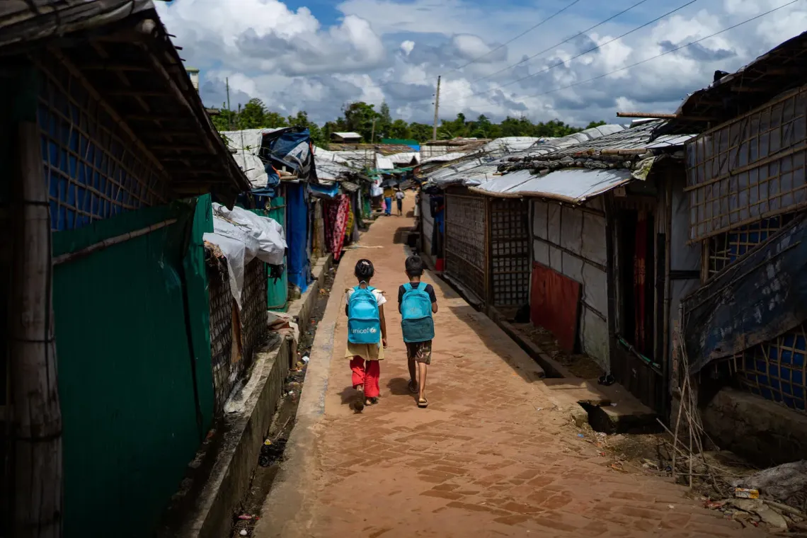 Bangladesh. Children carrying UNICEF backpacks walk through the dense shelters of Camp 9 at the Rohingya Camp in Cox's Bazar.