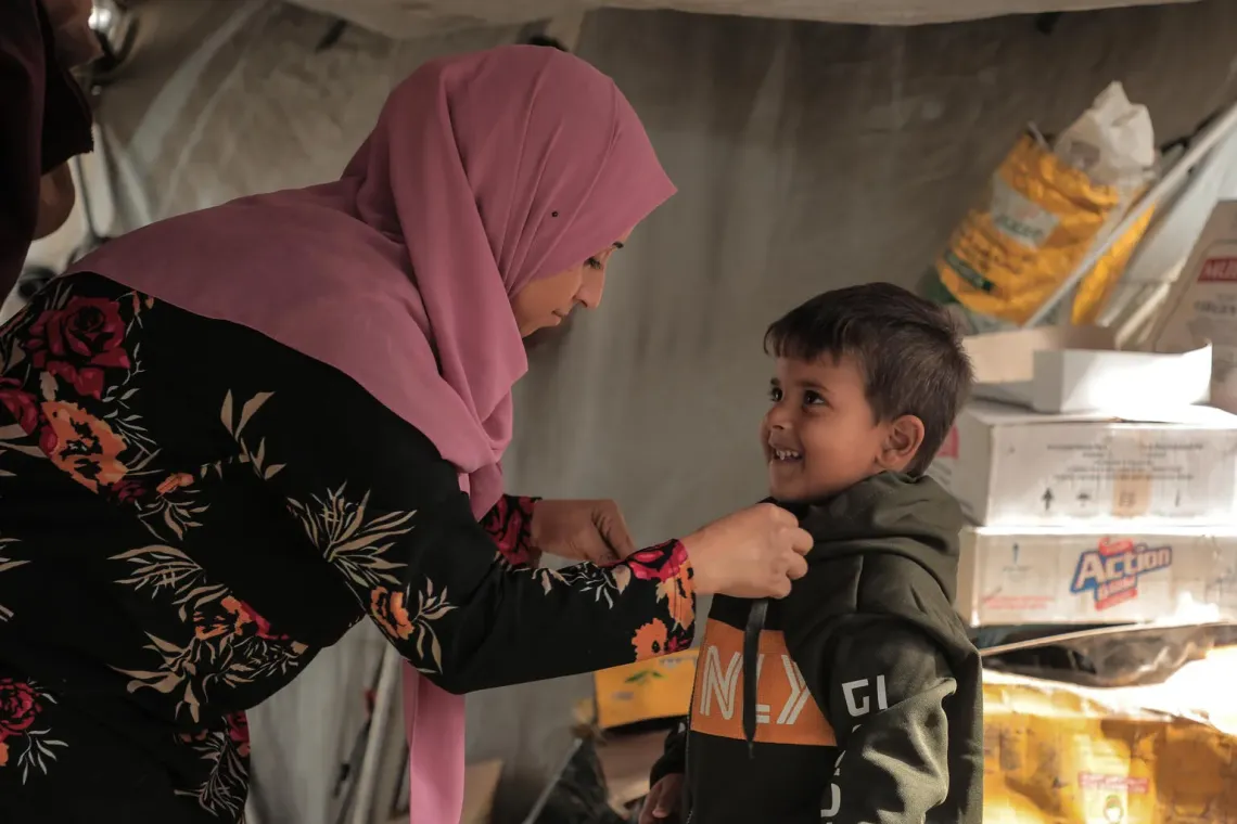 Gaza. Una madre ayuda a vestir a su hijo.
