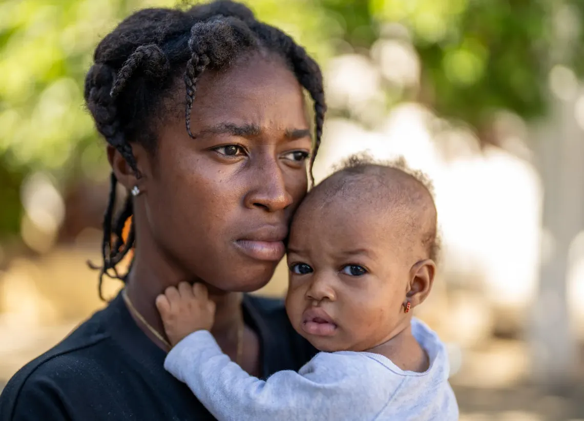 Haiti. A woman holds her child in the courtyard of a temporary shelter.