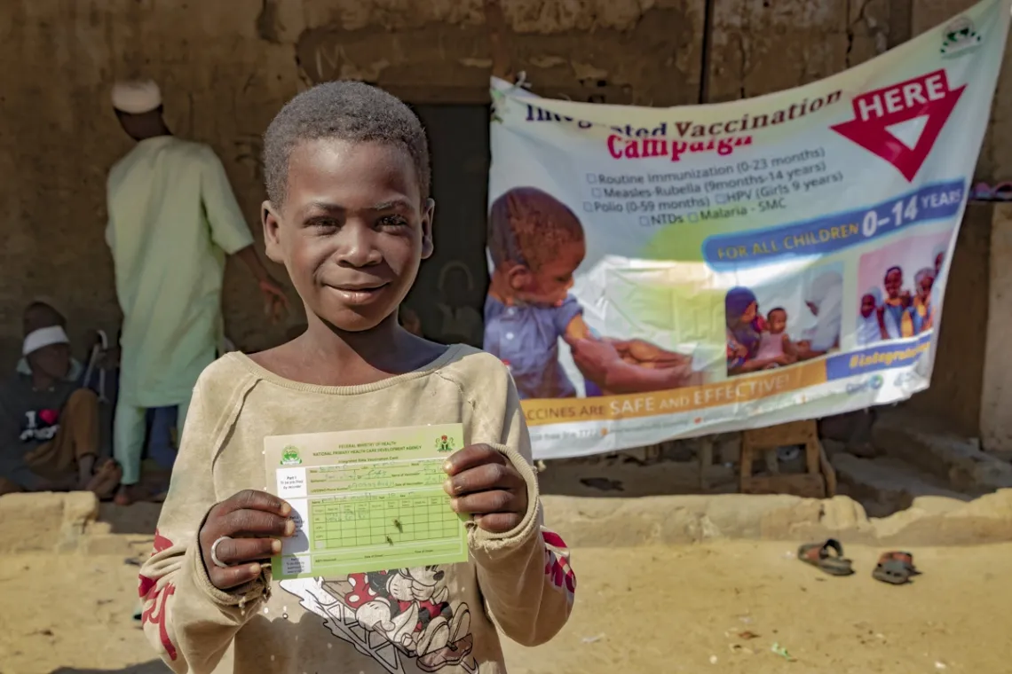 12-year-old Ma'azu shows his vaccination card after receiving the Measles Rubella vaccine