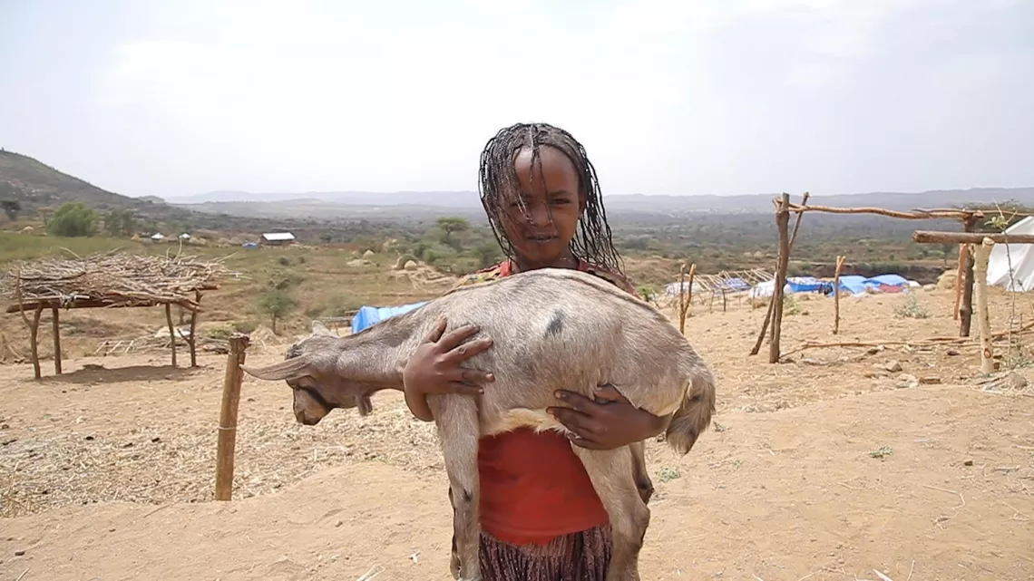 Ethiopia. A girl holds a goat in her arms.