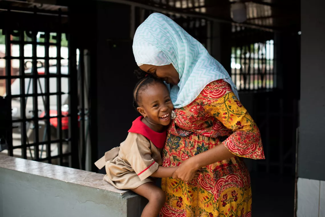 Liberia. A community mobilization officer holds her daughter.