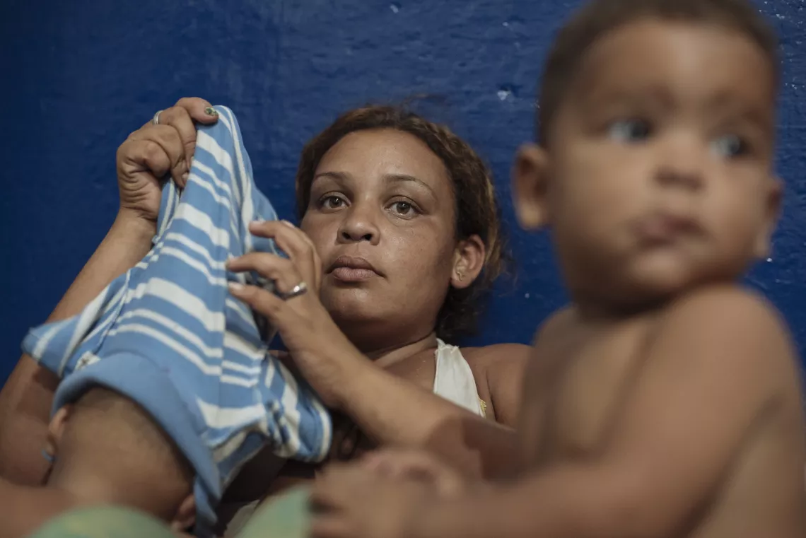 Colombia. Una mujer sentada con sus hijos en un centro de acogida