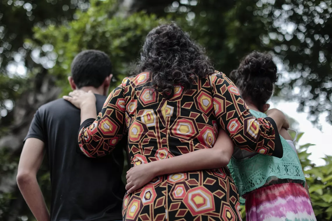 A mother puts her arms around her two children, El Salvador