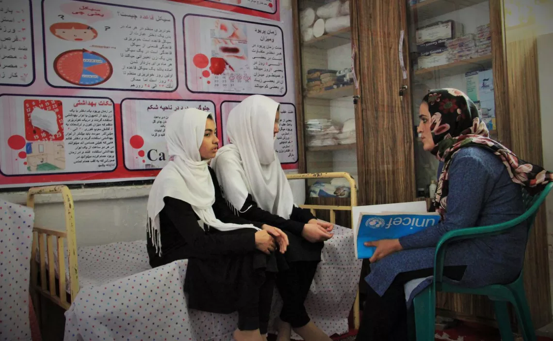 Deux filles assises &agrave; c&ocirc;t&eacute; d&rsquo;une femme tenant un livre &agrave; la main, Afghanistan
