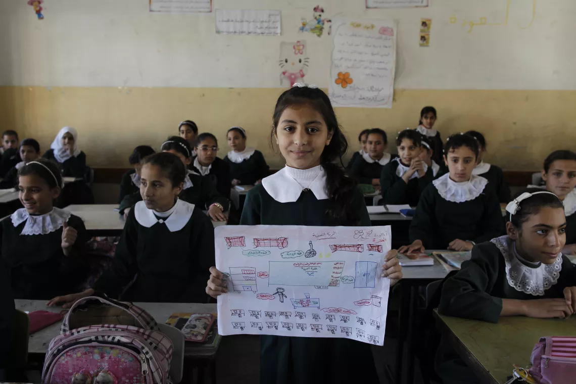 Nada holds up her drawing of her dream classroom.