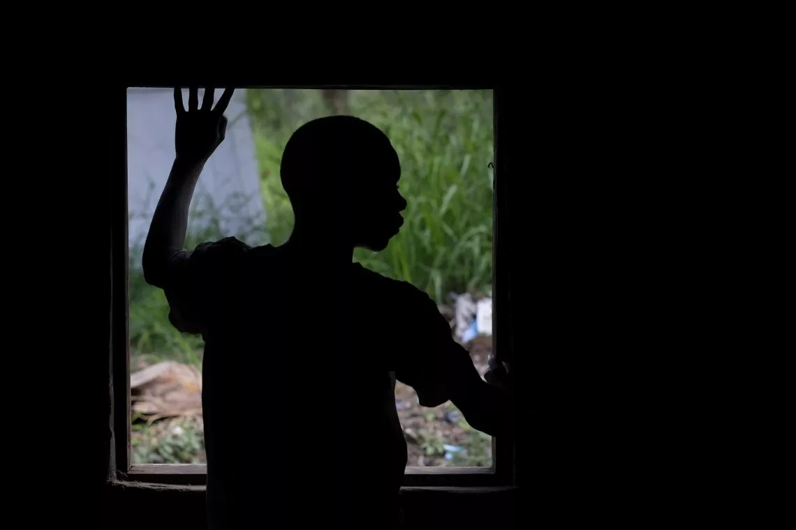 Boy stands in front of a window.
