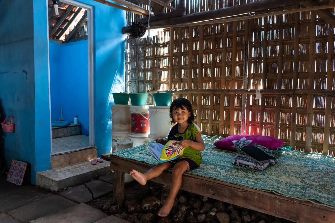 sanitation in indonesia: a young reads a book outside her family toilet 