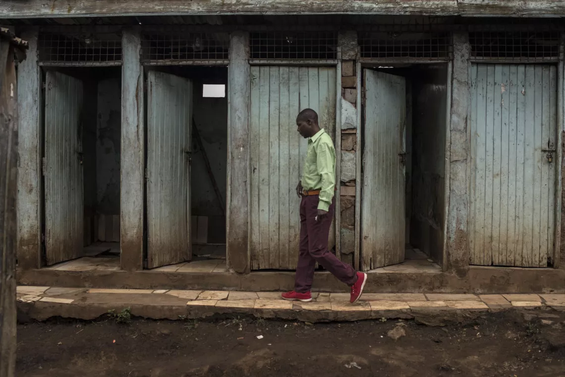 sanitation in kenya: man walks across public latrines