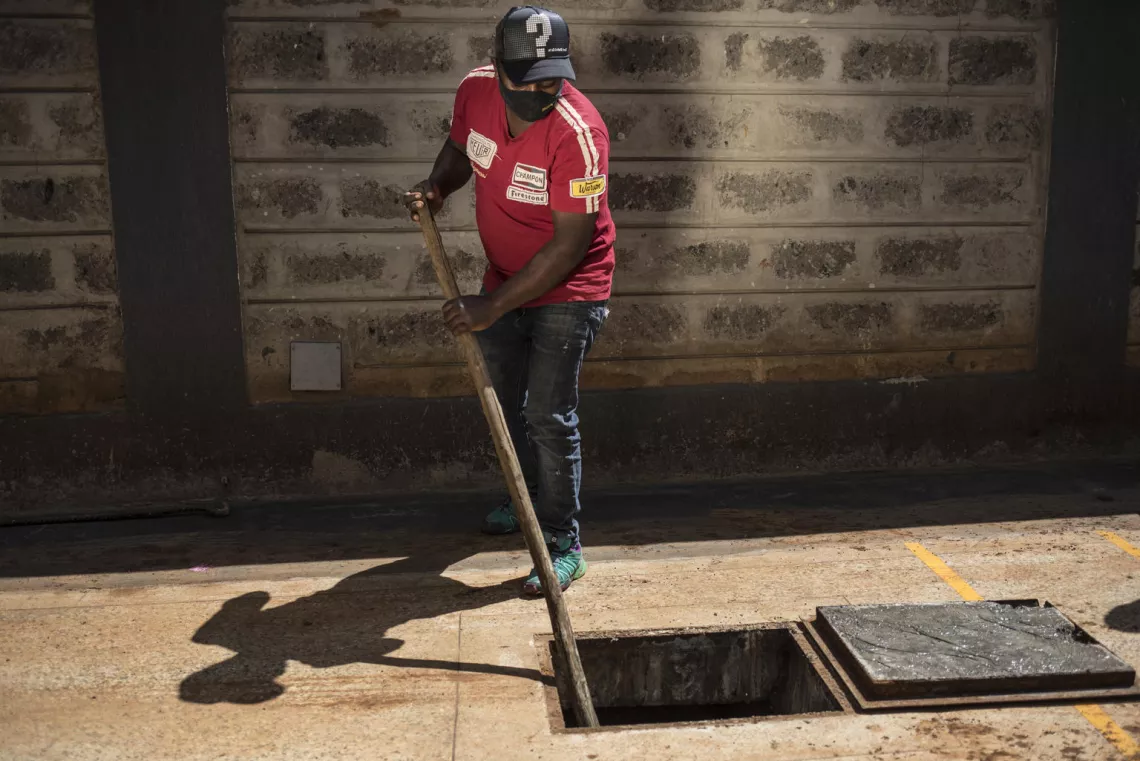 sanitation in kenya: man cleaning an underground septic tank