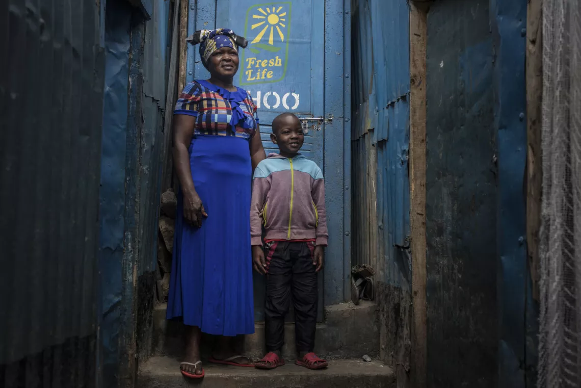 sanitation in kenya: woman and her grandchild outside a communal toilet