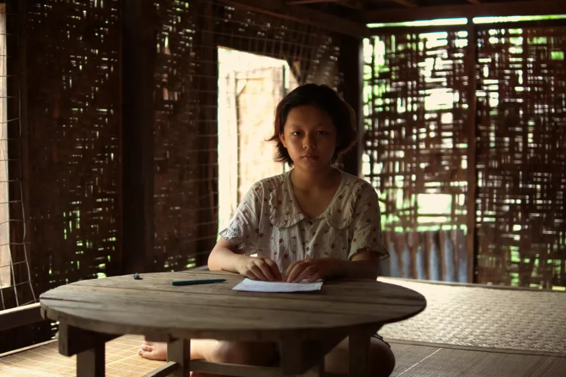 A girl sits at a low table holding her letter to adults.
