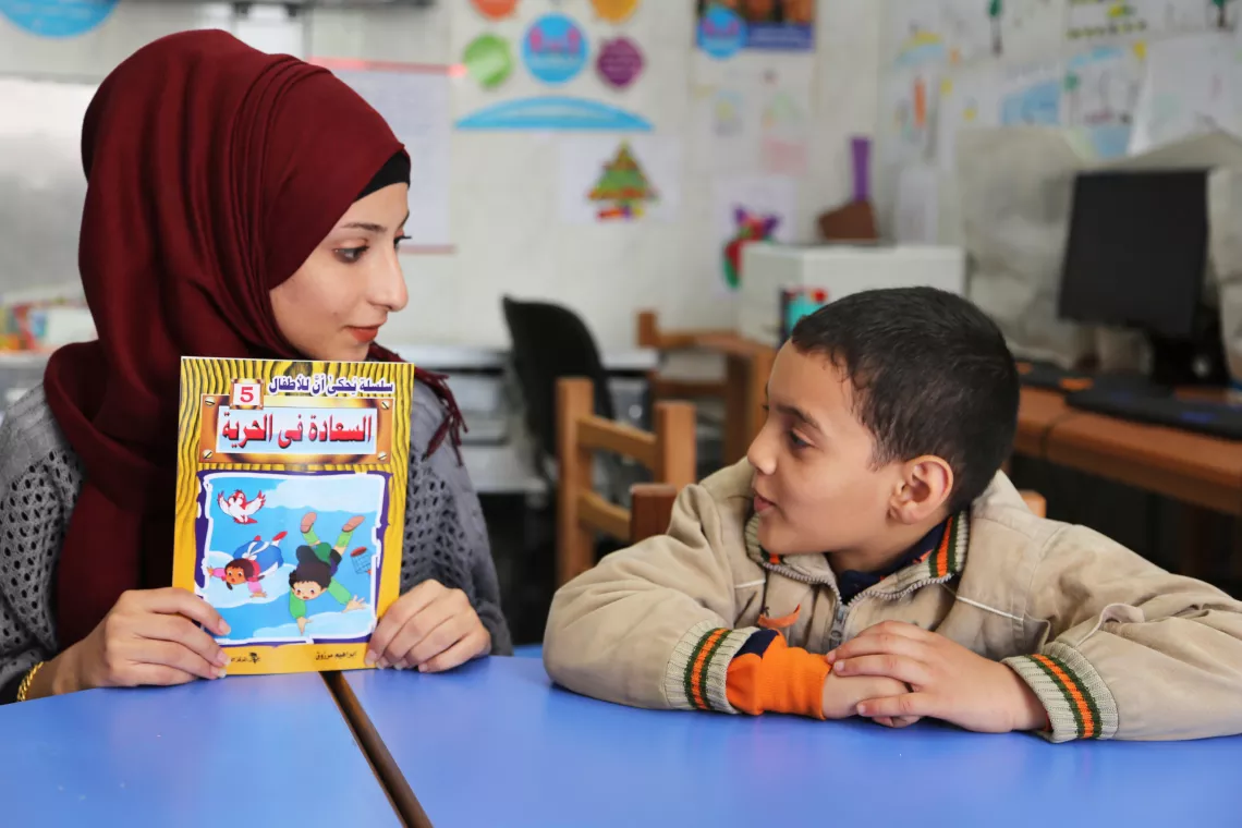 A teacher talks to a boy in a classroom