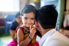 A 30 years old man playing with 2 years old daughter.