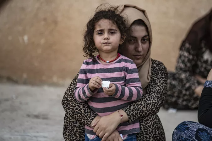On 11 October 2019 in the Syrian Arab Republic, a woman holds a child as families displaced from Ras Al-ain arrive in Tal Tamer, 75km southeast Ras of Al-ain, having fled escalating violence.