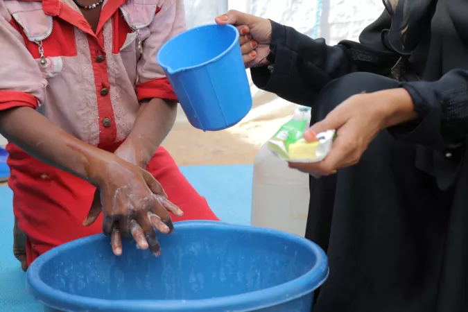 At a centre for families fleeing insecuirty, Esslam learns how to correctly handwash. She is being taught by Zahara a mother to mother peer educator, trained to spread health information and awareness, she also arrived in the IDP centre 3 years ago