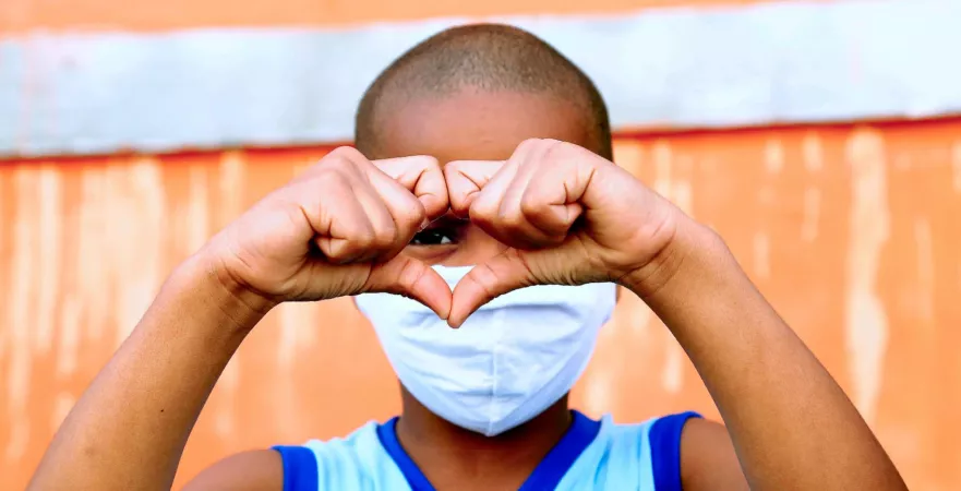 Boy peers through a heart formed with his hands