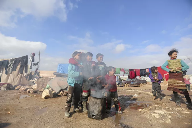 Children gather around a fire to keep warm in Kafr Losin Camp in northwest Syria on 19 January 2021