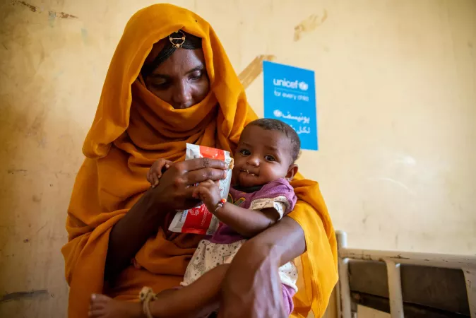 On 2 December 2024, Amna eats ready-to-use-therapeutic food at the health facility where she was referred for treatment in Aroma locality, Kassala state.