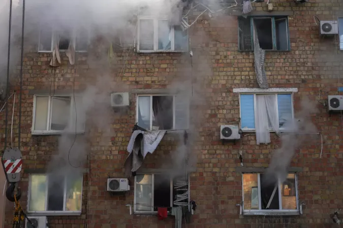 28 August 2025, Kyiv, Ukraine. Smoke pours from shattered windows of a residential block in Kyiv after a missile strike in the early hours of the morning. Curtains and debris hang outside the damaged apartments as rescue crews continue their search for survivors.