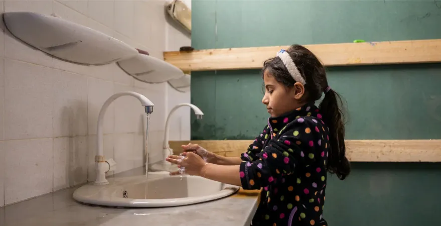 A girl washes her hands at a sink