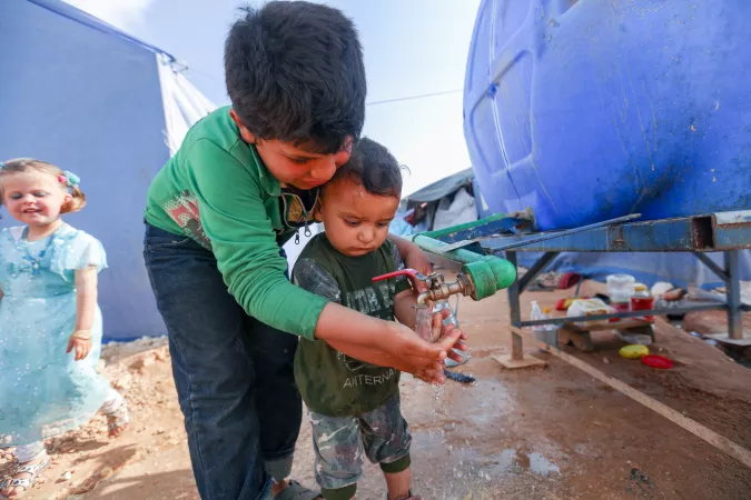 Children wash hands in the Maarat Misrin camp north of Idlib, Syrian Arab Republic