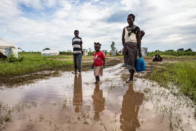 A family walking through flooded paddy fields