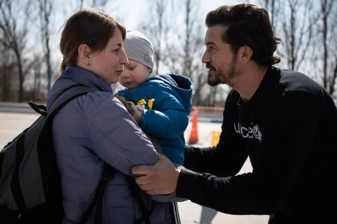 UNICEF Goodwill Ambassador Orlando Bloom talks to a mother and her son at the border crossing between Ukraine and Moldova at Palanca. 