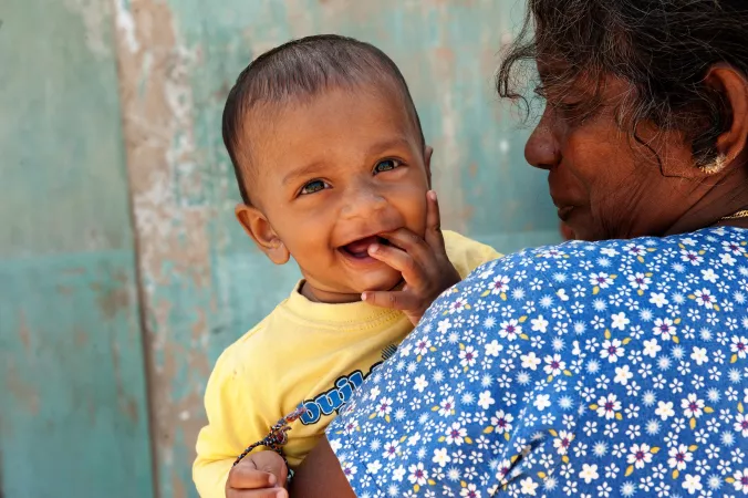 A smiling baby cared for by his mother. Sri Lanka 