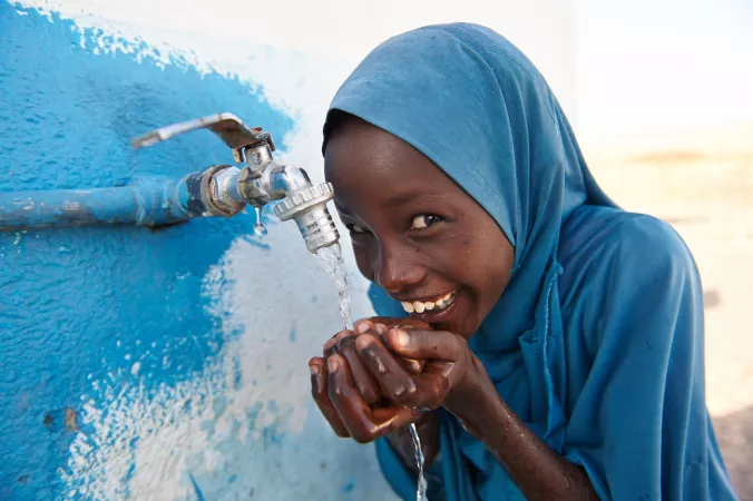 A girl child drinks safe water from a tap 
