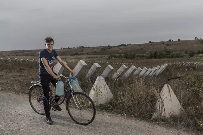 Ukraine. A boy sits on his bicycle next to a field of antitank barriers in the Donetsk region.