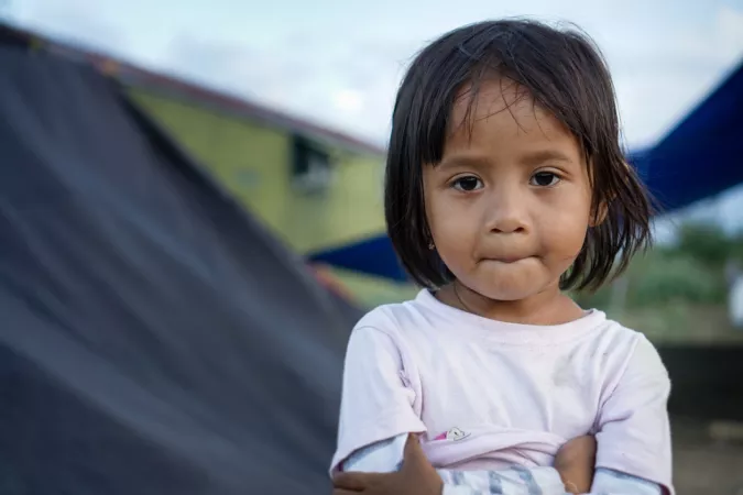 A young girl standing in front of temporary shelters
